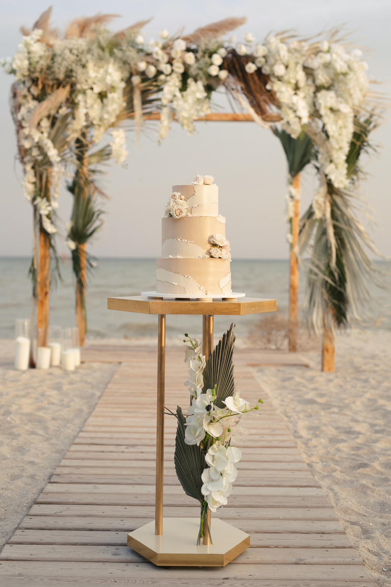 Wedding Cake at a Beach Wedding on the Background of a Beautiful Arch for an Exit Ceremony.